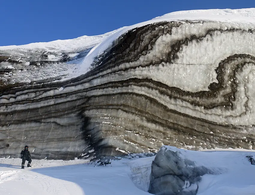 Winter fieldwork insights can be special. Here the clarity of ice structures in a medial moraine deformed by glacier surging has been enhanced by the lack of melting by solar radiation during the dark season. After the onset of summer, the structures become almost invisible. The photo was taken on a snow scooter excursion to Vestre Grønfjordbreen. Photo: Andy Hodson/UNIS